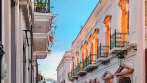Una calle bordeada de edificios históricos, balcones y plantas colgantes.