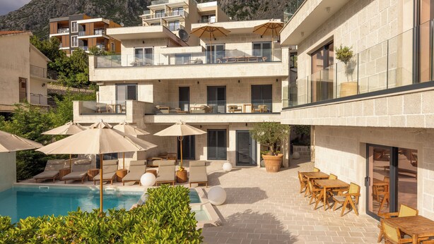 Un hotel de varios pisos con piscina, zona de estar exterior y vistas a la montaña.