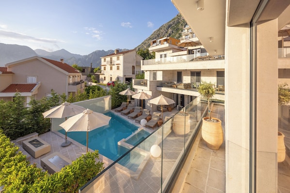A residential building with a rooftop pool, outdoor seating, and a mountain backdrop.