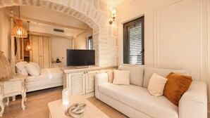 Una sala de estar con un sofá, una mesa de centro, un televisor y un arco de piedra.