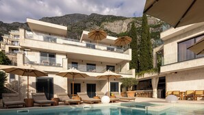 Un hotel moderno con piscina, mobiliario exterior y vistas a las montañas.