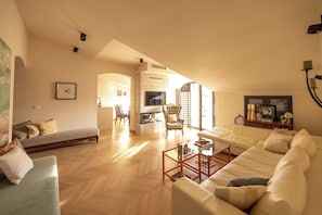 A spacious living room with a fireplace, a sofa, a coffee table, and a television.