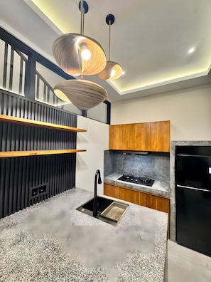 Una cocina moderna con estufa integrada, pileta negra y armarios de madera.