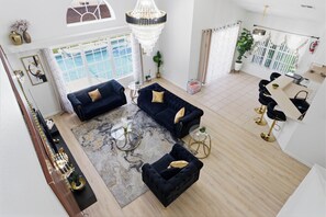 A spacious living area with a large window, a chandelier, and a pool view. - 9 Minutes to Disney Pool + Theater + Game Room (Kissimmee)