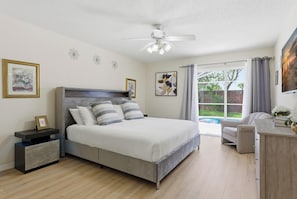 A bedroom with a bed, a nightstand, a chair, and a view of the outdoors. - 9 Minutes to Disney Pool + Theater + Game Room (Kissimmee)