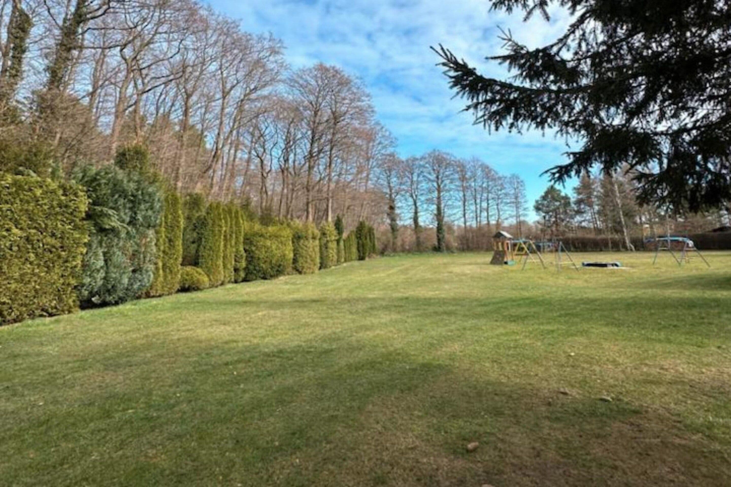 A grassy yard with a wooden play structure and a small shed.