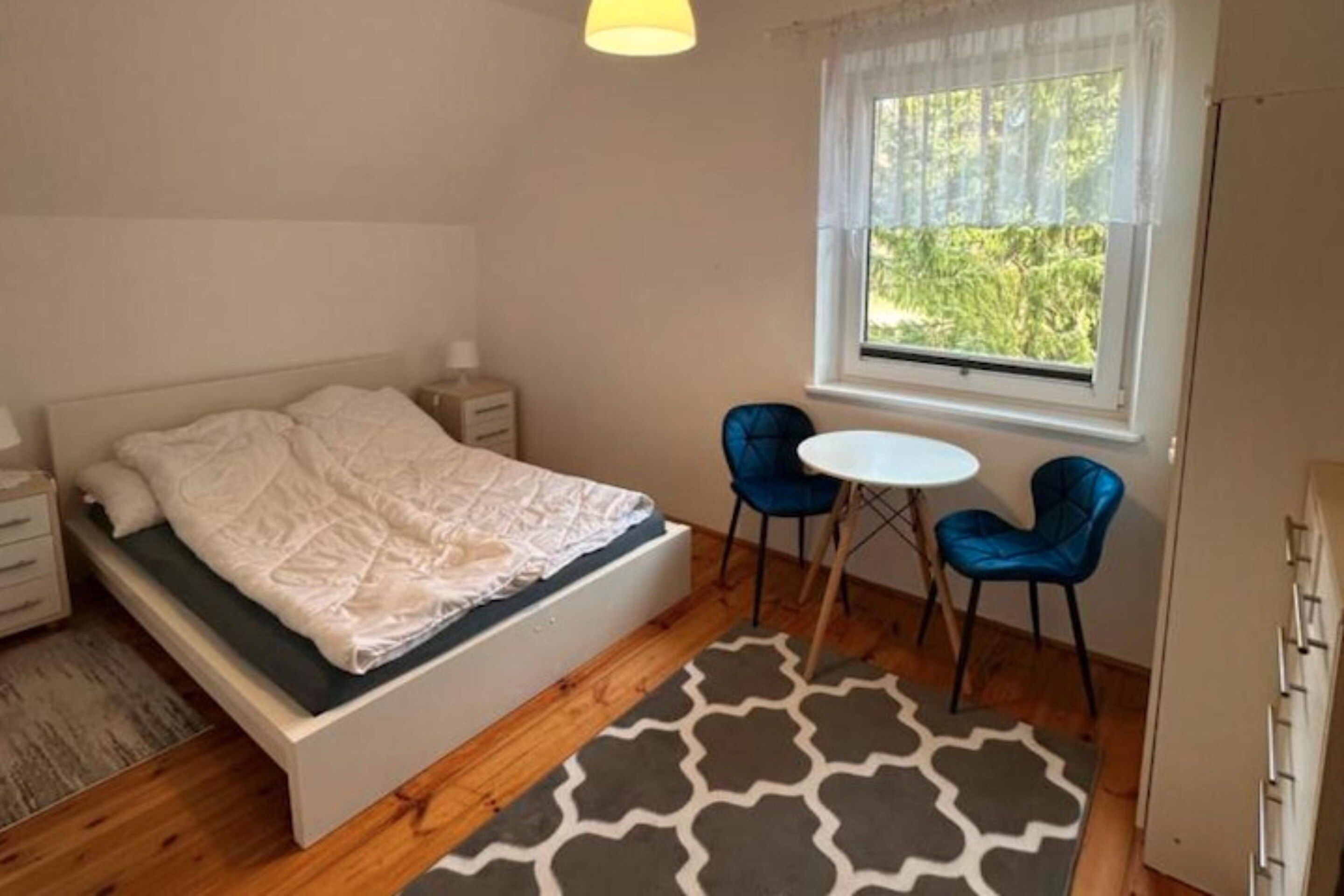 A bedroom with a bed, bedside tables, a window with a view, and two chairs.