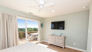 A bedroom with a bed, a dresser, a television, and a balcony with a view. - Soundside, Ocean views, Private Pool, Comm Amenities-  MS826, Ciao Bella (Corolla)
