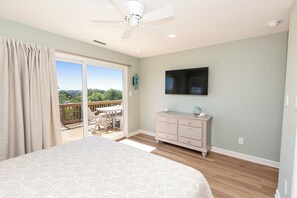 A bedroom with a bed, a dresser, a television, and a balcony with a view. - Soundside, Ocean views, Private Pool, Comm Amenities-  MS826, Ciao Bella (Corolla)