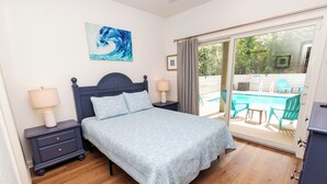 A bedroom with a bed, nightstands, a painting, and a view of an outdoor pool area. - Soundside, Ocean views, Private Pool, Comm Amenities-  MS826, Ciao Bella (Corolla)