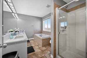 A bathroom with a shower, a bathtub, a sink, and a window. - Luxury Urban Oasis in Prime Location (Airdrie)