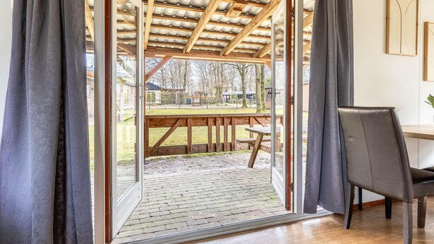A room with a wooden ceiling, a sliding glass door leading to an outdoor area with a picnic table, and a chair. - 2 bedroom gorgeous home in Erm (Erm)