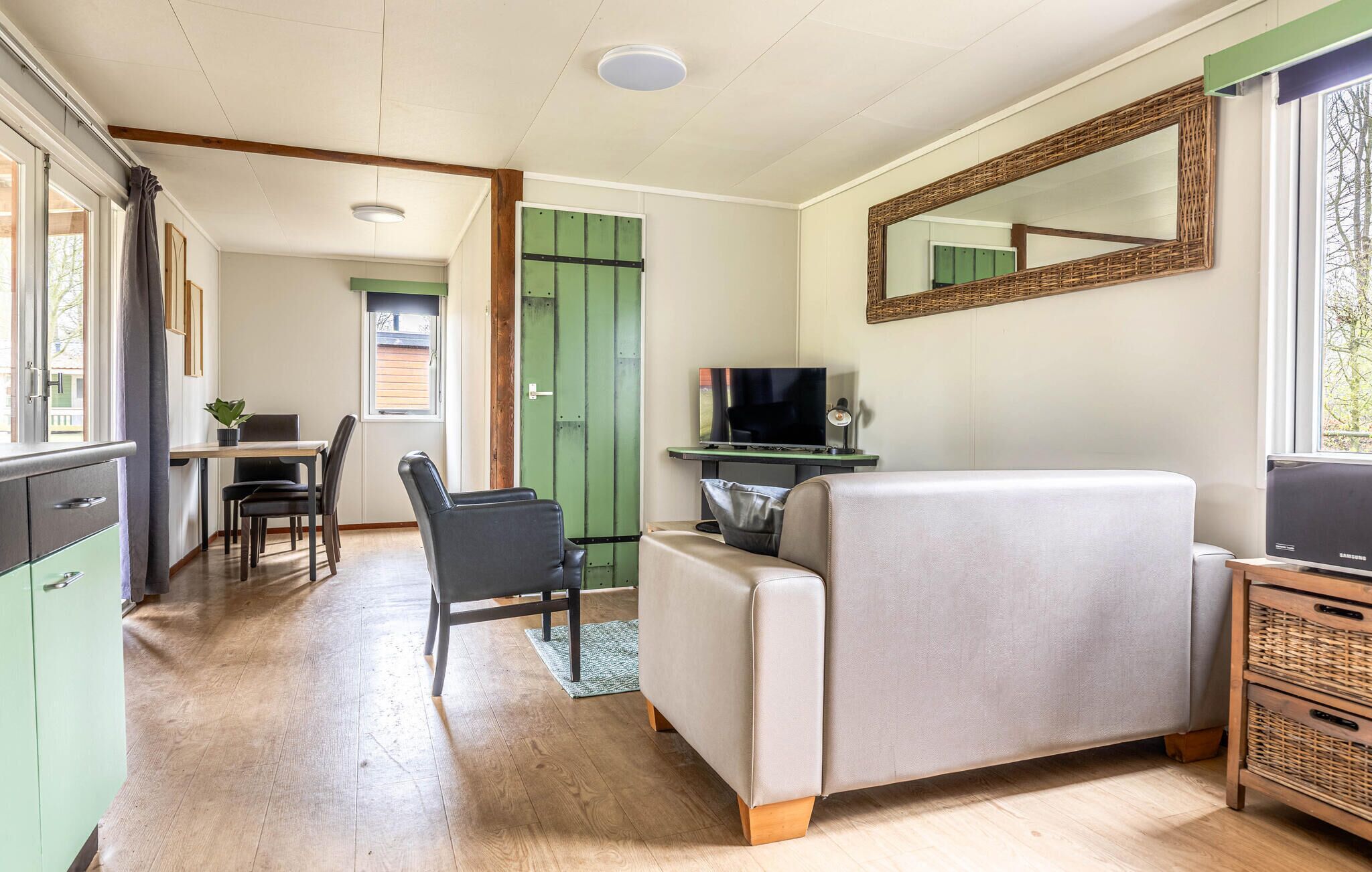 Un espacio habitable compacto con sofá, televisión, comedor y un espejo.