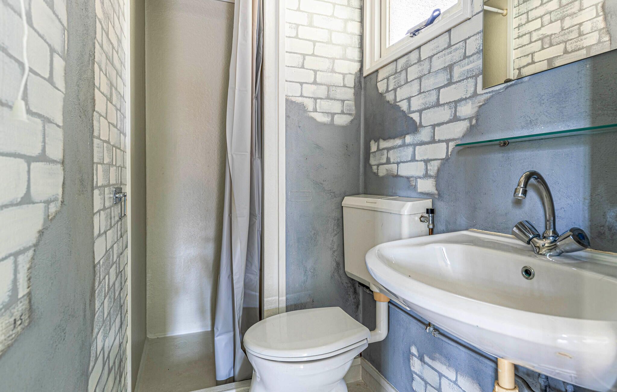 A bathroom with a white toilet, a shower curtain, a sink with a faucet, and a toilet tank.