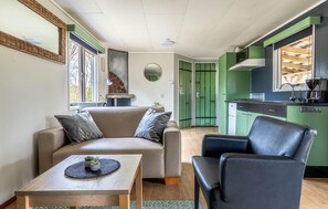 Ein gemütlicher Wohnbereich mit einer Couch, einem Couchtisch, einem Sessel und einer Küchenzeile.