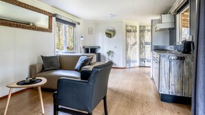 Un soggiorno moderno con divano, poltrona, tavolino e angolo cottura con piano cottura e lavello.
