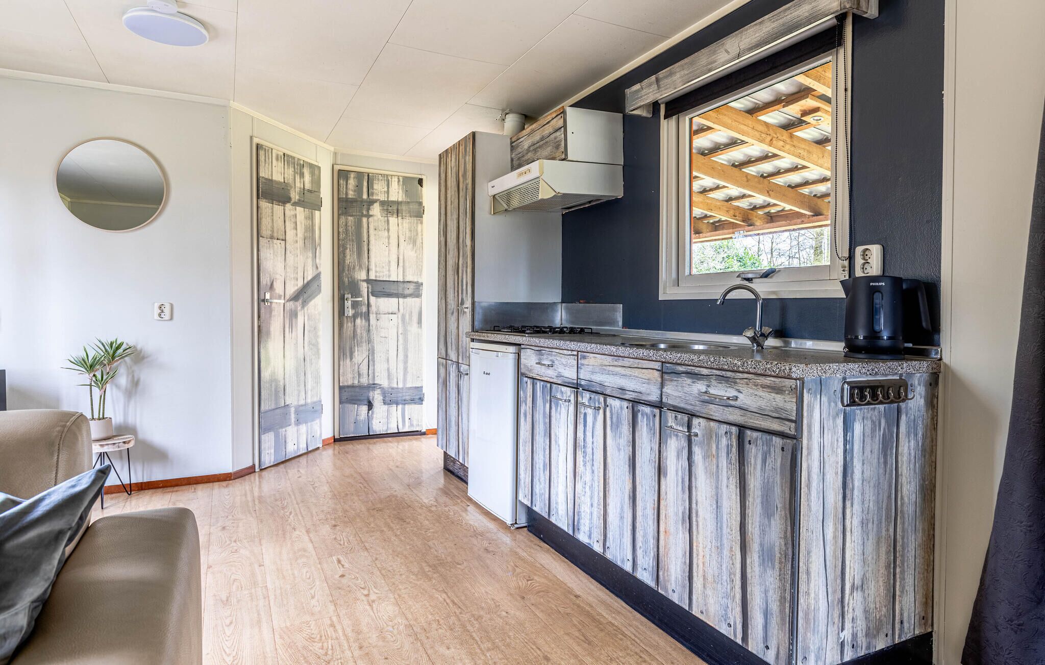 Una cocina con armarios de madera, estufa integrada y ventana con vistas a la estructura del techo.