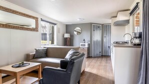 Un espace de vie compact comprenant un canapé, une petite table, un coin cuisine et un espace repas.