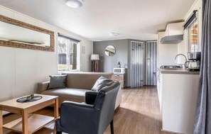 Ein kompakter Wohnbereich mit Sofa, kleinem Tisch, Küchenzeile und Essplatz.