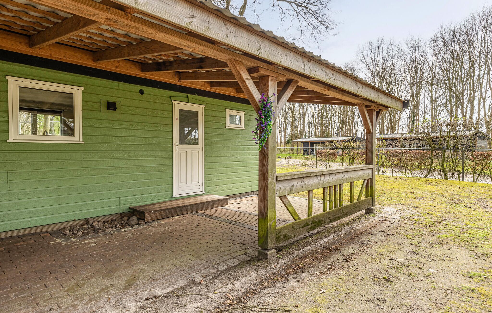 Een groen houten gebouw met een veranda, een deur en ramen.