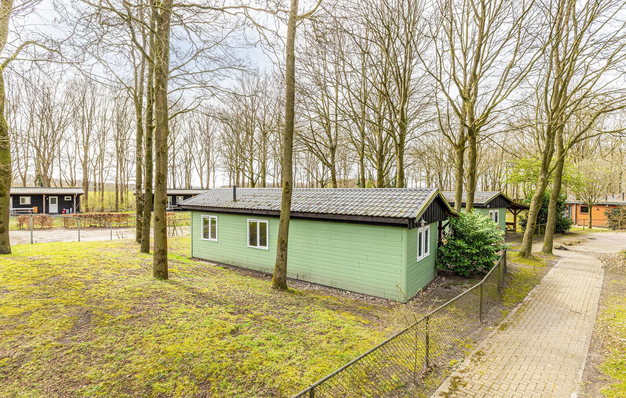 Eine kleine, einstöckige Holzhütte mit geneigtem Dach, umgeben von Bäumen und einem gepflasterten Weg.