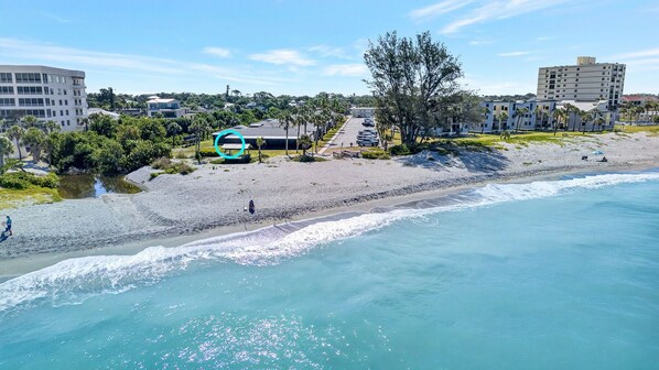 A coastal area with a beach, a bus, and buildings in the background.