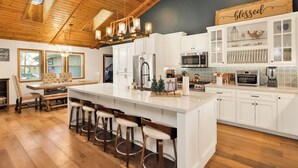 Een ruime keuken met een groot schiereiland, barstoelen en moderne apparatuur.