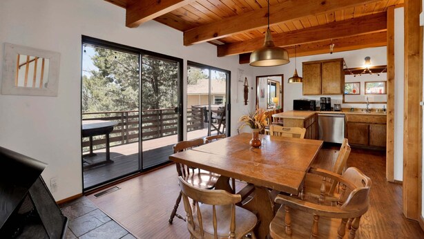 Un comedor amplio con una mesa y sillas de madera, una cocina con armarios de madera, y un amplio ventanal corredero que da a una terraza exterior.