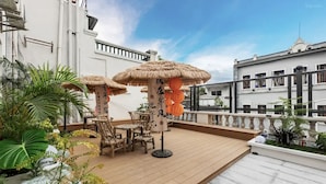 A rooftop terrace with wooden furniture, thatched umbrellas, and potted plants. - Boni Hotel Guangzhou Huangsha Station (Guangzhou)