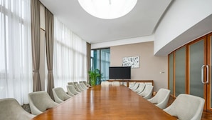 A conference room with a long wooden table, beige chairs, a large window with curtains, a television, and a map on the wall. - Boni Hotel Guangzhou Huangsha Station (Guangzhou)
