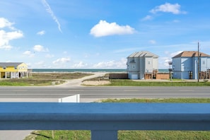 Eine Küstenstraße mit Gebäuden, einem klaren Himmel und einem Strand im Hintergrund.