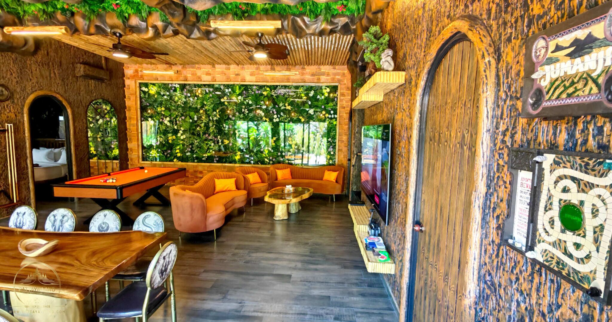 A room with a pool table, a sofa set, a television, and a wall with a mural.