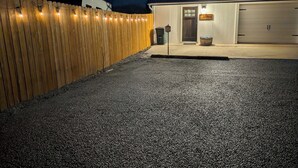 A building with a gravel driveway, a wooden fence, and a garage door.
