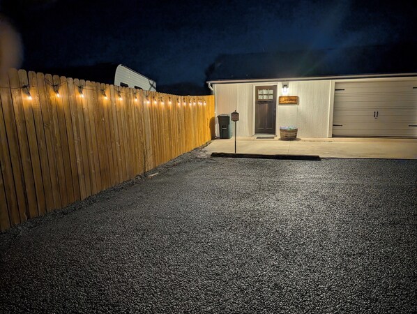 A building with a gravel driveway, a wooden fence, and a garage door.