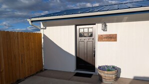 A building with a metal roof, a wooden fence, a door with a window, and a sign that reads 'CANYON GLOW RETREAT.'