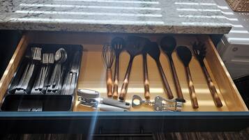 Un cajón de cocina con utensilios y una cafetera.