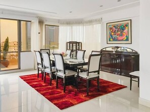 A dining area with a table, chairs, and a red rug.