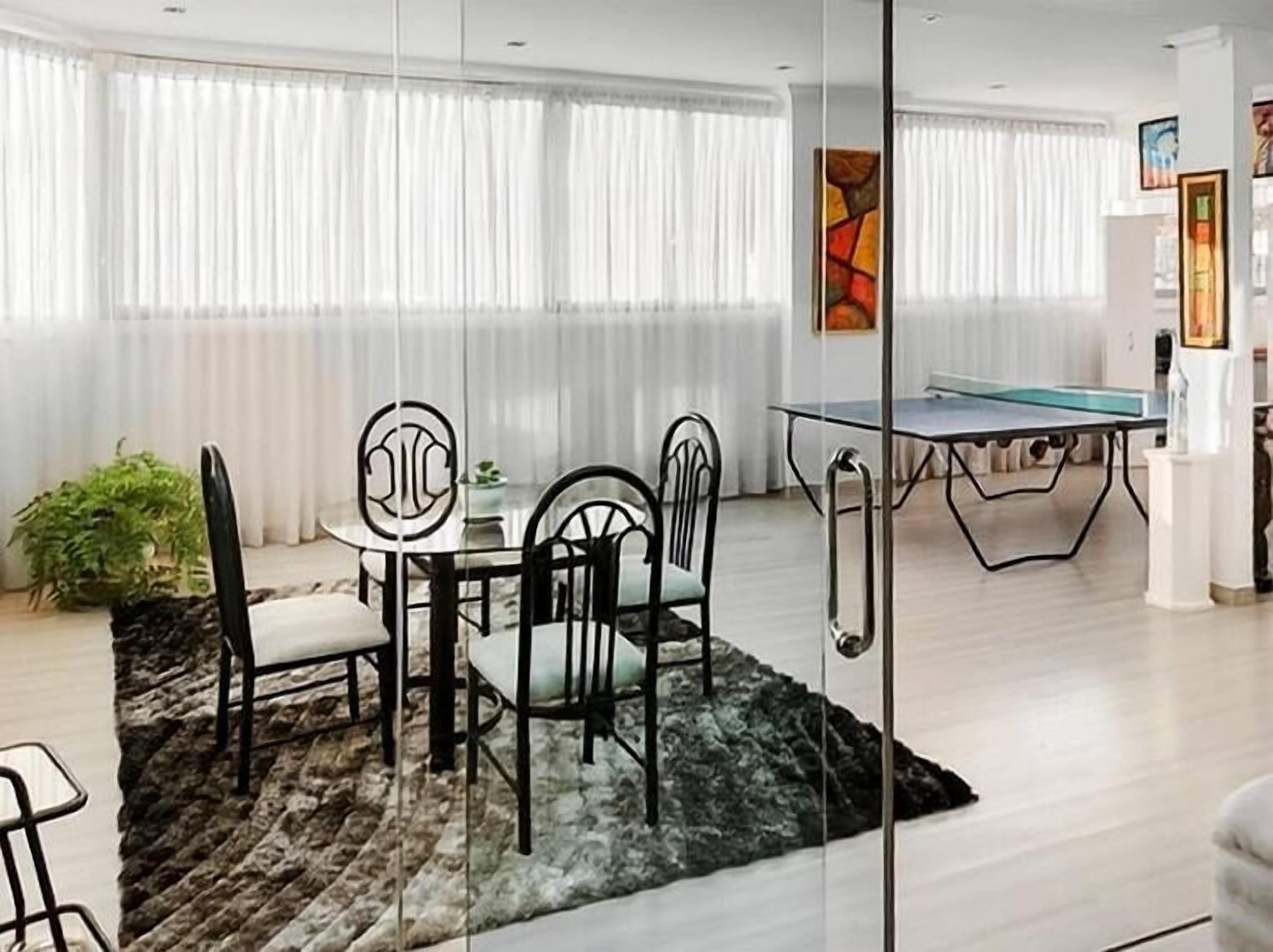 Un comedor con una mesa y sillas, una mesa de ping pong y una planta en maceta.