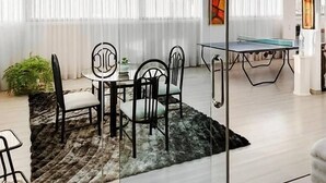 Un espace repas avec une table et des chaises, une table de ping-pong et une plante en pot.
