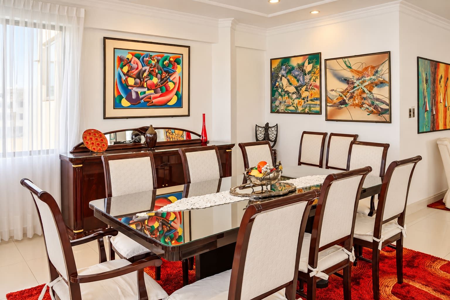 A dining room with a rectangular table, six chairs, and three framed artworks on the walls.