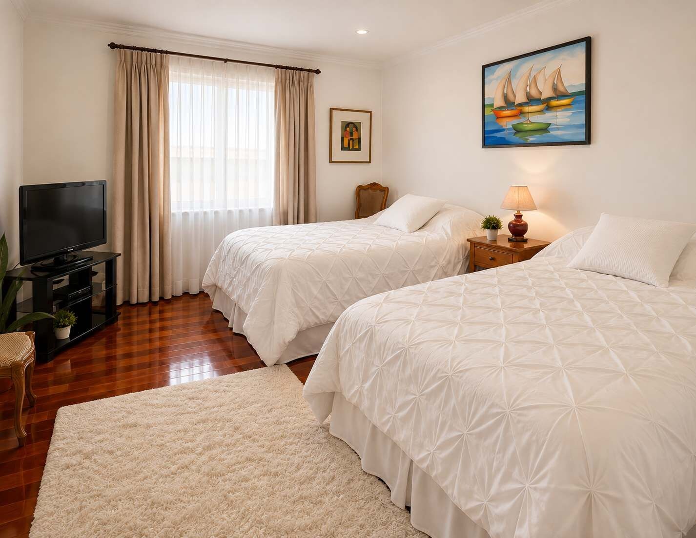 A hotel room with two beds, a television, a painting, and a window with curtains.