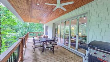 A covered outdoor deck with a table and chairs, a grill, and a star ceiling fan.