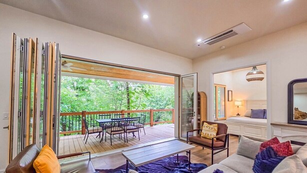 A modern living room with a sofa, coffee table, and a dining area with chairs and a table.