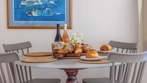 Een eettafel met een schilderij van boten, flessen, glazen en croissants.
