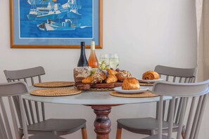 Ein Esstisch mit einem Gemälde von Booten, Flaschen, Gläsern und Croissants.