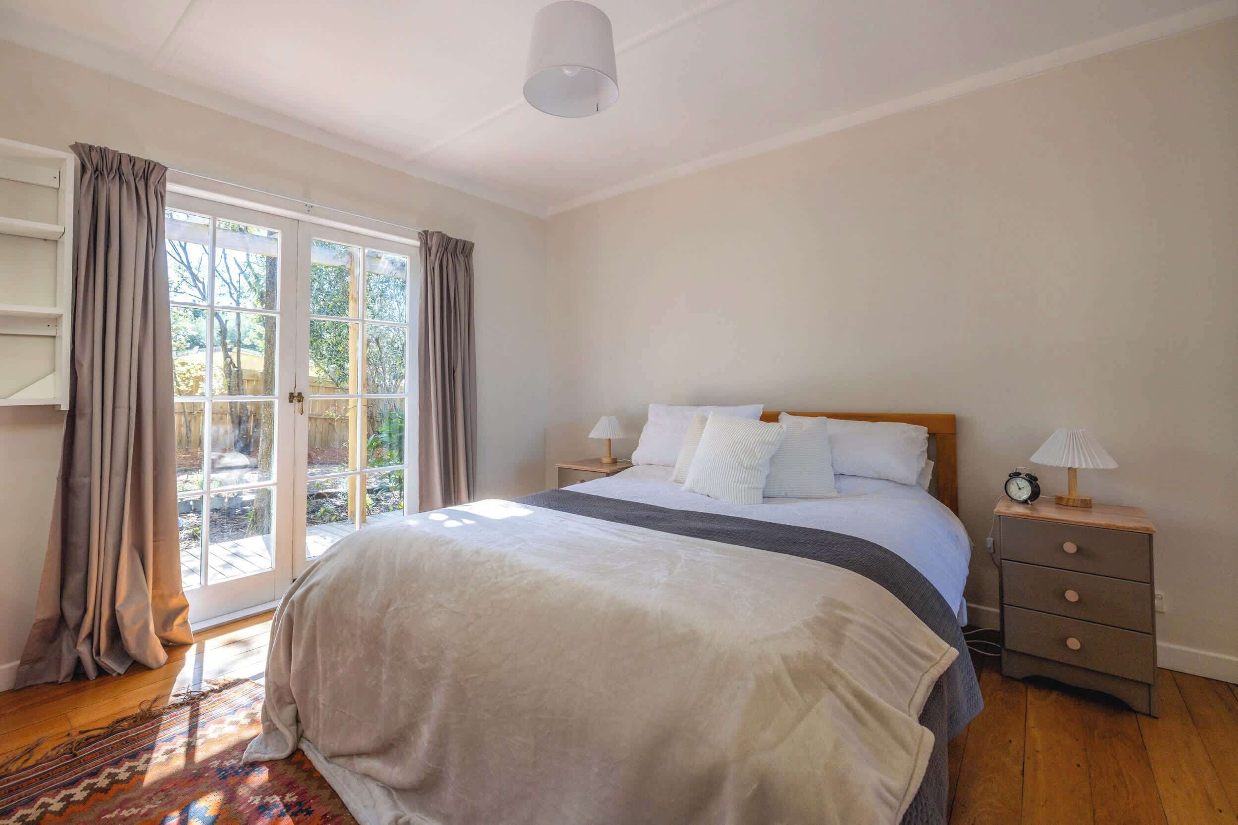 A bedroom with a bed, a nightstand, a lamp, and a window with curtains.