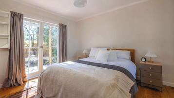 A bedroom with a bed, a nightstand, a lamp, and a window with curtains.