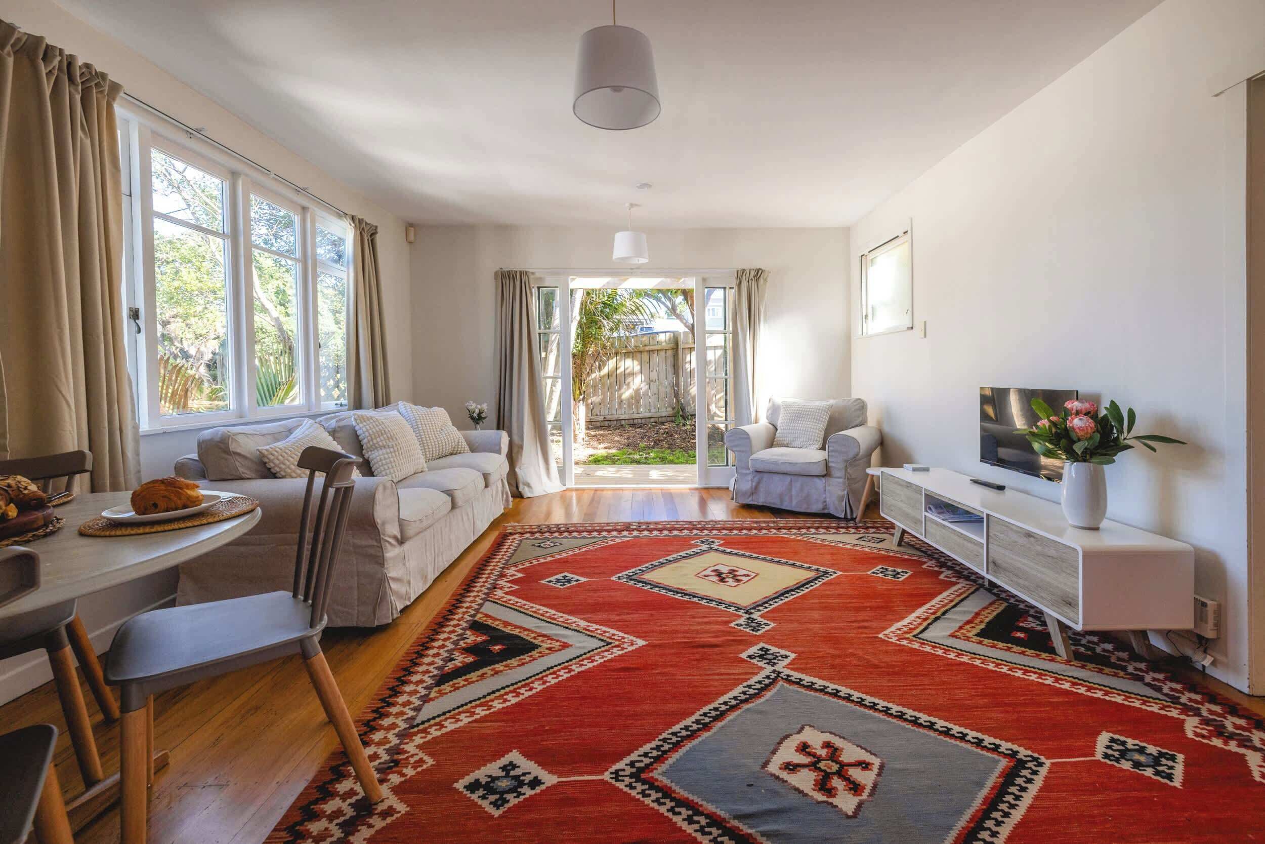 A spacious living area with a sofa, a dining table, and a TV on a white cabinet.