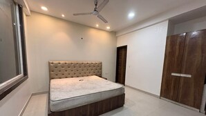 A bedroom with a bed, a ceiling fan, a wardrobe, and a window. - Hotel Twamev Peeragarhi (New Delhi)