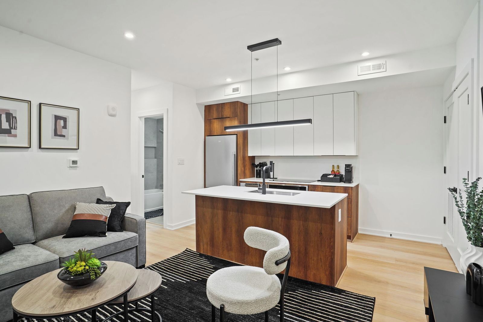 A modern kitchen with a central island, a grey sofa, and a coffee machine.